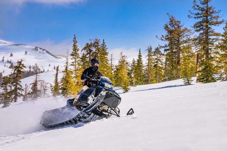 Snowmobiler riding through alpine winter landscape